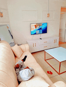 a child laying on a couch in front of a television