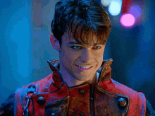 a young man in a red jacket is smiling and looking at the camera .