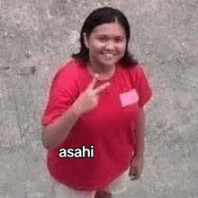 a woman in a red shirt is giving the middle finger while standing on the ground .