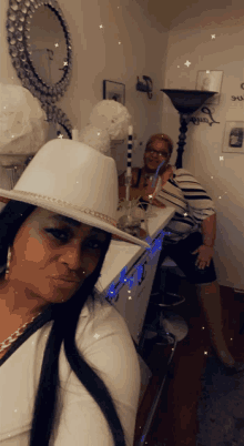 a woman wearing a white hat takes a selfie with another woman