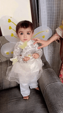 a little girl wearing a fairy costume is standing on a couch