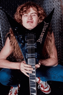 a man playing a guitar with the word megadeth on the neck