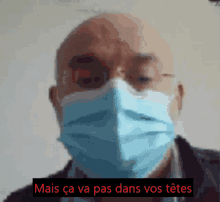 a man wearing a face mask with the words mais ca va pas dans vos tetes behind him