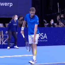 a man in a blue shirt is holding a tennis racquet on a tennis court in front of a sign that says psa