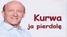 a bald man in a blue shirt is standing in front of a sign that says `` kurwa ja pierdole '' in polish .