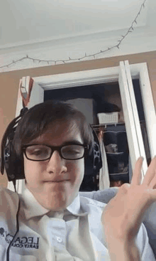 a young man wearing glasses and headphones is sitting on a couch in a room .