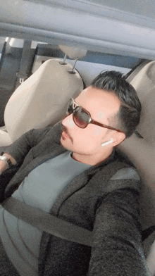 a man wearing sunglasses and ear buds is sitting in a car