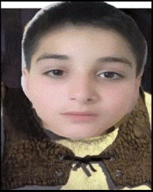 a close up of a young boy 's face with a brown vest around his neck