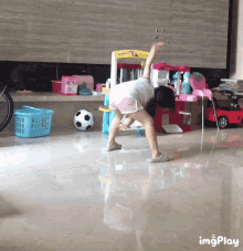 a little girl is doing a yoga pose in front of a kitchen set that says hello kitty on it