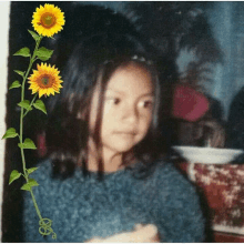 a young girl with sunflowers in her hair looks at the camera