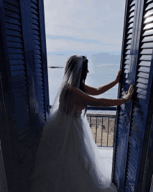 a woman in a wedding dress looks out a window