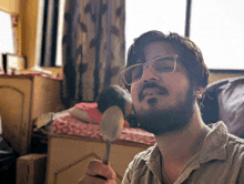 a man with glasses and a beard is holding a spoon