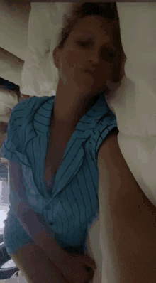 a woman in a blue striped shirt is laying in a bed