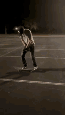 a man in a white shirt and black hat is standing on a skateboard in a parking lot at night .