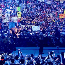 a crowd of people watching a wrestling match with a sign that says ' i can 't lease petticoat '