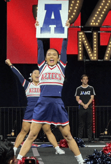 a cheerleader holding up a sign that says aztecs on it