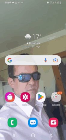 a phone screen shows a man wearing sunglasses and a white shirt