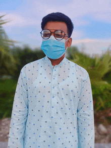 a man wearing a face mask and glasses stands in front of a palm tree