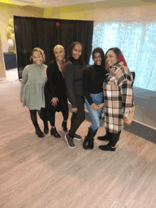 a group of women are posing for a picture in a room with an exit sign