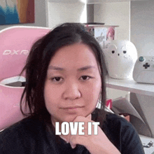 a woman is sitting in front of a pink chair with her hand on her chin .