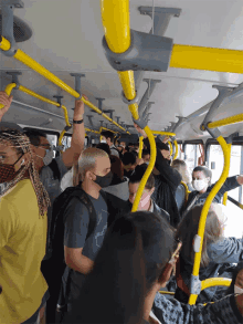 a man wearing a mask rides a bus with many other people