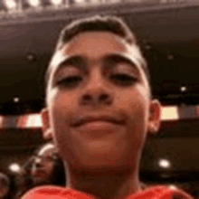 a young boy is taking a selfie in front of a crowd of people in a theater .