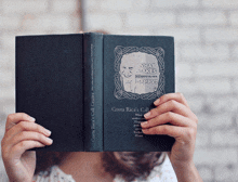 a woman covers her face with a book called what makes happy