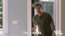 a man in a green shirt is standing in front of a door and says these hands