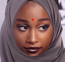 a woman in a hijab with a red dot on her forehead .