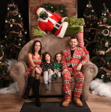 a family sitting on a couch with a grinch sitting on top of them