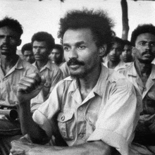 a man with a beard is sitting in a crowd of people