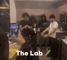 a group of people are gathered in a kitchen with the lab written on the bottom right