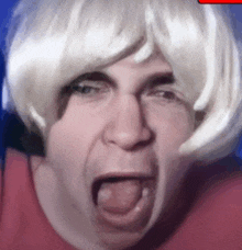 a man wearing a blonde wig is making a funny face with his mouth open .