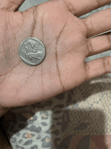 a hand is holding a silver coin that says 2 rand