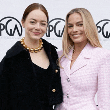 two women are posing for a picture in front of a pg logo