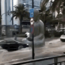 a statue of a man is standing in the middle of a flooded street next to a no parking sign .