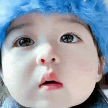 a close up of a baby wearing a blue hat and looking at the camera .