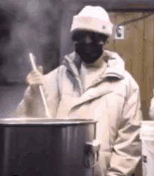 a man wearing a mask and a hat is stirring a pot with a ladle .