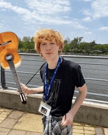 a young man holding a guitar with a lanyard around his neck that says mcdonald 's squad