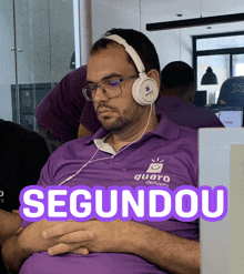 a man wearing headphones and a purple shirt that says quero delivery is sleeping