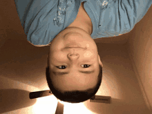 a young boy is upside down in a room with a ceiling fan