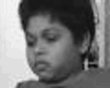 a black and white photo of a young boy making a face .