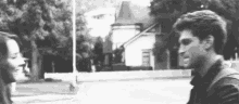 a man and a woman are standing next to each other in front of a house in a black and white photo .