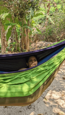 a woman is laying in a green hammock on the beach