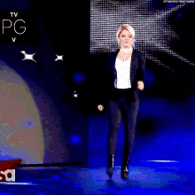 a woman in a suit is walking on a stage with the word raw on it