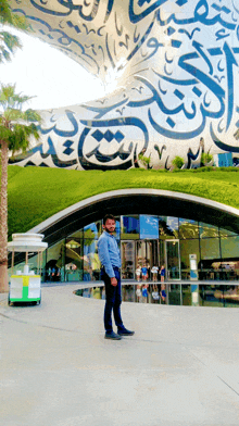 a man stands in front of a building with arabic calligraphy on it