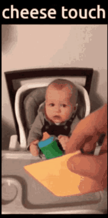 a baby in a high chair with a piece of cheese in front of it