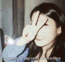 a woman covering her face with her hand and the words yo cuando soy solo de martina