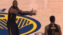 a basketball player named lebron james is standing on a basketball court with his hands outstretched .