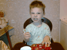 a young boy is sitting in a chair with a toy car in front of him